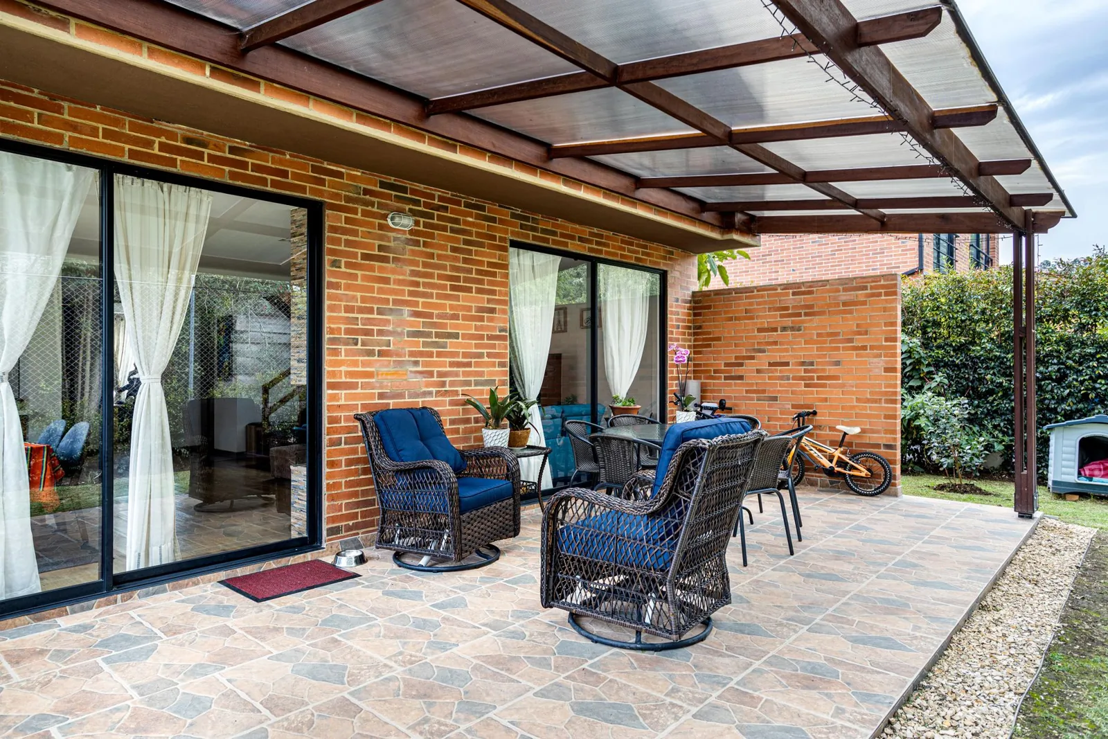 covered patio ideas — a pergola covering a backyard patio with string lights and lounge furniture